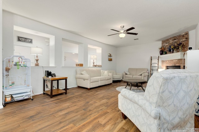 living room with ceiling fan, a fireplace, and hardwood / wood-style floors