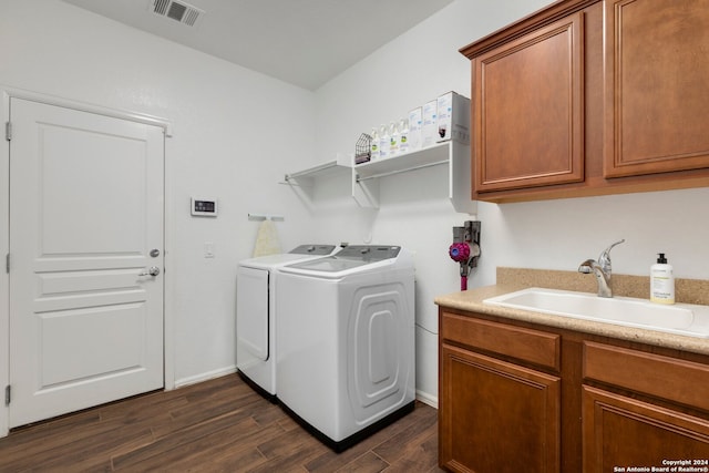 clothes washing area with dark hardwood / wood-style flooring, washer and dryer, sink, and cabinets