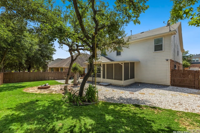 rear view of property with a fire pit, a sunroom, a lawn, and a patio area