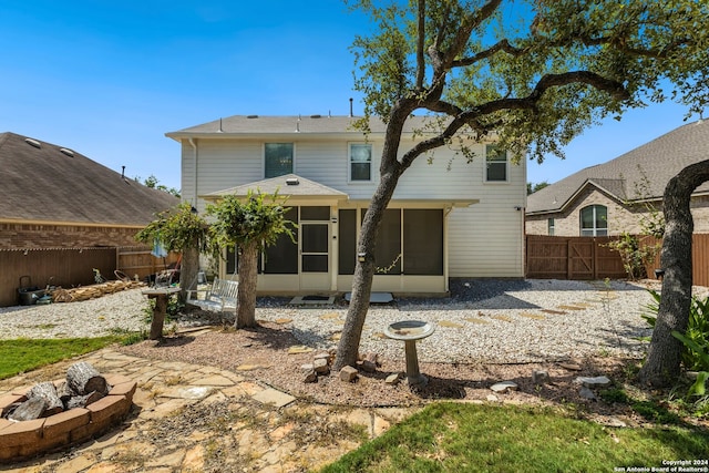 back of house featuring a sunroom, a patio, and an outdoor fire pit