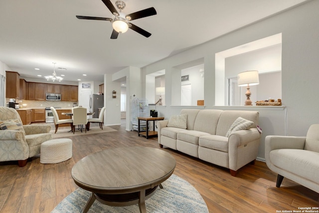 living room featuring ceiling fan with notable chandelier and wood-type flooring