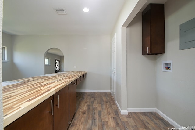 kitchen featuring electric panel, dark brown cabinetry, butcher block countertops, and dark hardwood / wood-style flooring