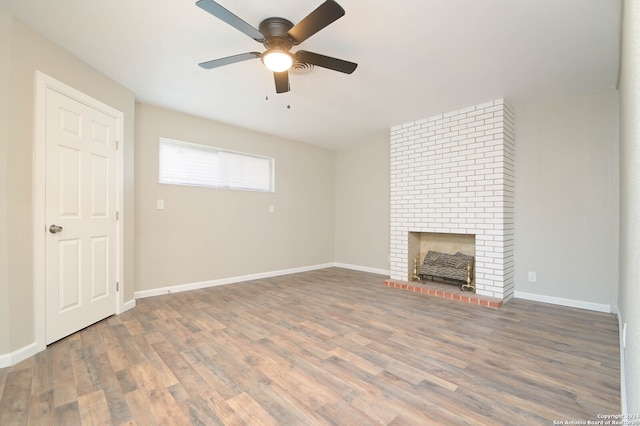 unfurnished living room featuring ceiling fan, hardwood / wood-style flooring, and a brick fireplace