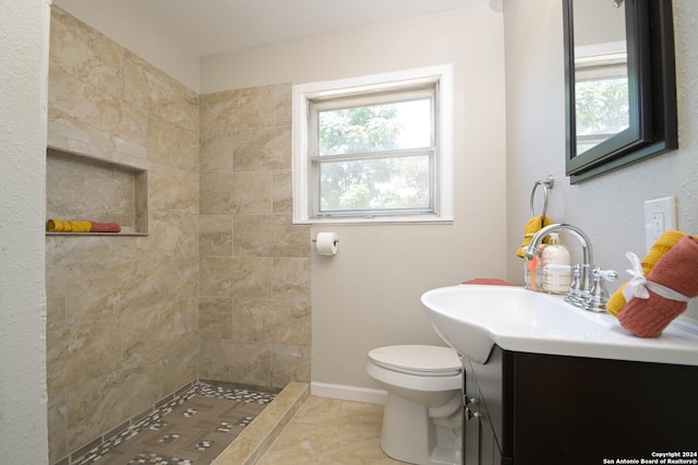 bathroom featuring tile patterned floors, tiled shower, toilet, and vanity