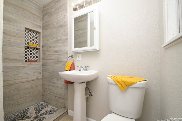 bathroom featuring toilet and a tile shower