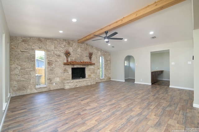 unfurnished living room featuring vaulted ceiling with beams, hardwood / wood-style floors, ceiling fan, and a stone fireplace