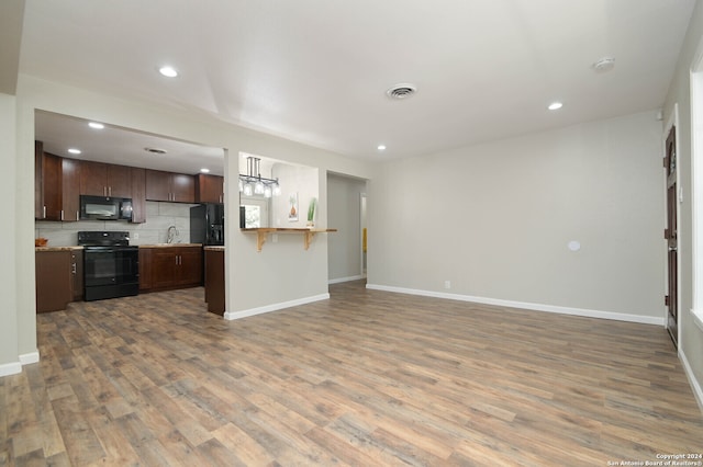 kitchen featuring black appliances, backsplash, hardwood / wood-style floors, and sink