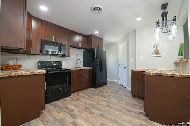 kitchen featuring light wood-type flooring, decorative light fixtures, black appliances, wooden counters, and decorative backsplash