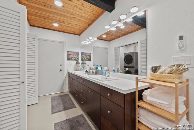 bathroom with wood ceiling, beam ceiling, vanity, and stacked washer and clothes dryer