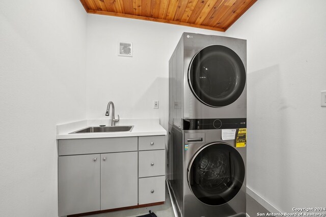 washroom featuring wood ceiling, sink, cabinets, and stacked washing maching and dryer