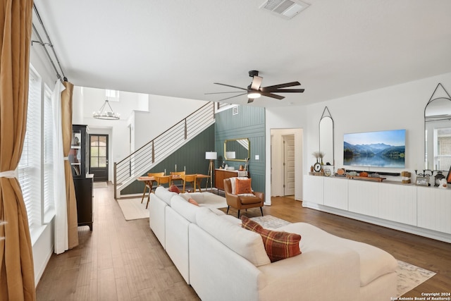 living room with hardwood / wood-style floors and ceiling fan with notable chandelier