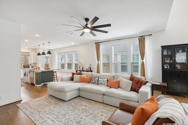 living room with light wood-type flooring, sink, and ceiling fan