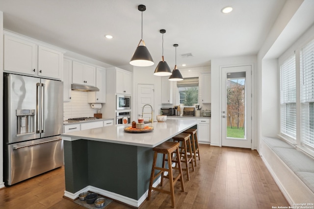 kitchen with white cabinets, stainless steel appliances, and a center island with sink