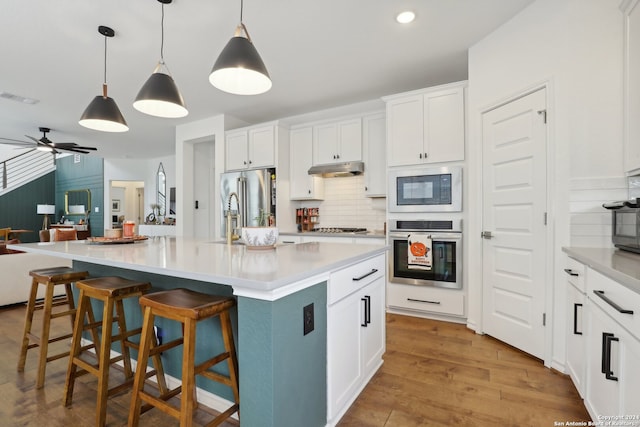 kitchen featuring white cabinets, stainless steel appliances, a spacious island, ceiling fan, and pendant lighting