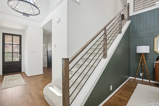 foyer featuring a high ceiling, an inviting chandelier, hardwood / wood-style floors, and wooden walls