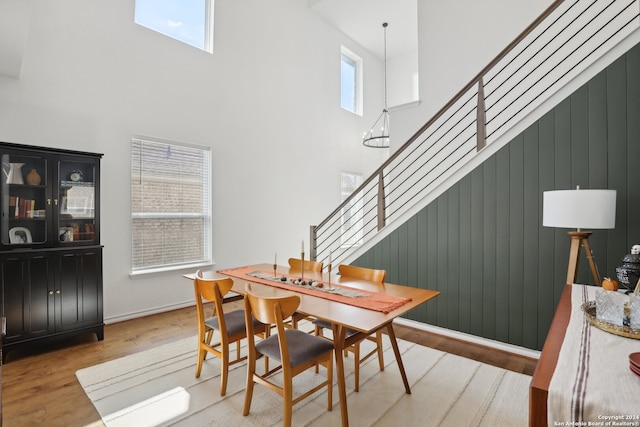 dining area featuring wooden walls, a high ceiling, and light hardwood / wood-style floors