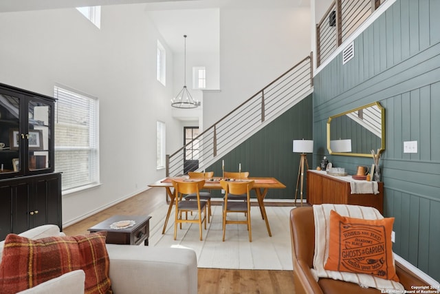 dining space with hardwood / wood-style floors, plenty of natural light, a chandelier, and a towering ceiling