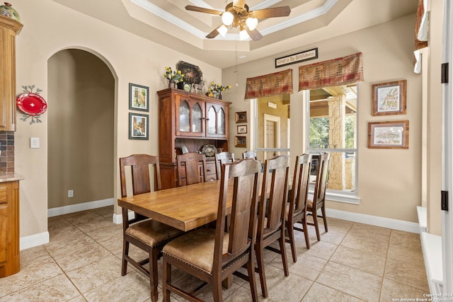 dining area featuring ceiling fan, a raised ceiling, and ornamental molding