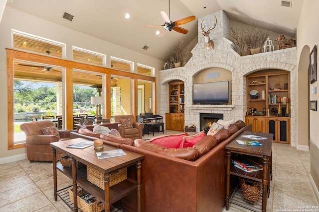 tiled living room featuring built in features, a stone fireplace, high vaulted ceiling, and ceiling fan