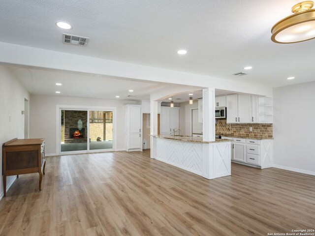 kitchen featuring light wood-type flooring, light stone countertops, white cabinetry, sink, and tasteful backsplash