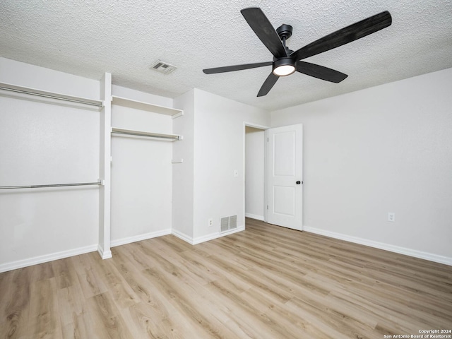 unfurnished bedroom with a textured ceiling, light hardwood / wood-style flooring, ceiling fan, and a closet