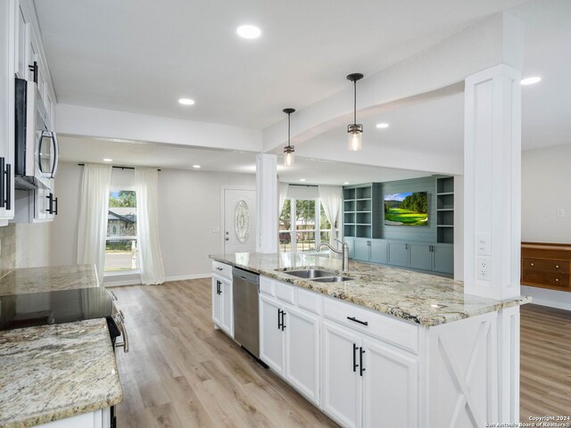 kitchen featuring a kitchen island with sink, sink, light stone countertops, appliances with stainless steel finishes, and white cabinets