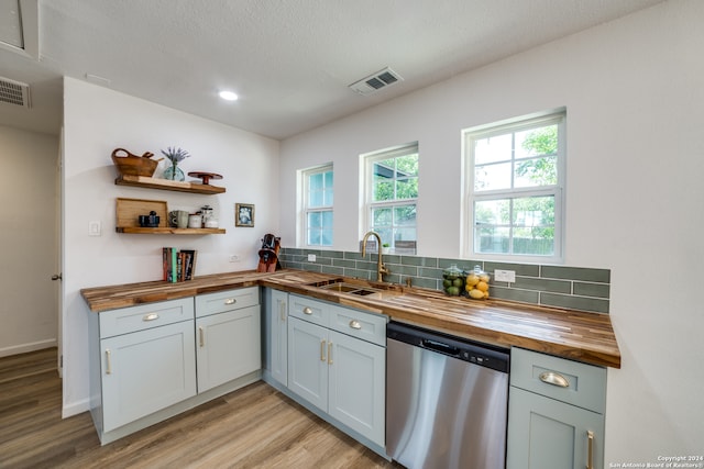 kitchen with light hardwood / wood-style flooring, sink, decorative backsplash, butcher block counters, and stainless steel dishwasher