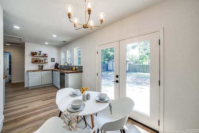 dining space featuring a healthy amount of sunlight, a notable chandelier, sink, and light wood-type flooring