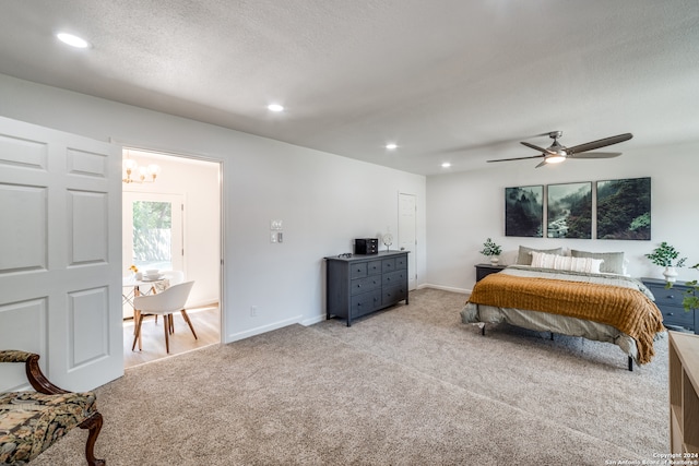 bedroom with ceiling fan with notable chandelier, light carpet, and a textured ceiling