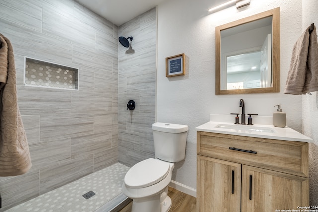 bathroom featuring tiled shower, hardwood / wood-style floors, toilet, and vanity