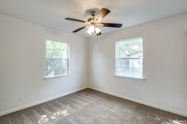 carpeted empty room with ceiling fan and plenty of natural light