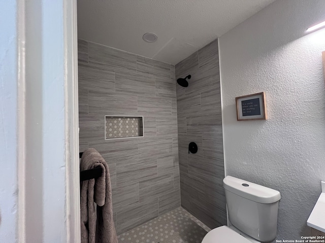 bathroom with vanity, toilet, and tiled shower