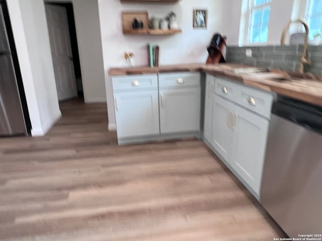 kitchen with dishwasher, light hardwood / wood-style flooring, backsplash, white cabinetry, and butcher block counters