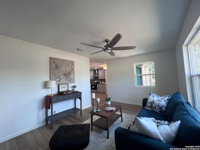 living room with a textured ceiling, ceiling fan, and wood-type flooring