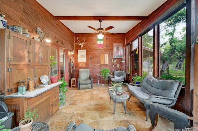 sunroom featuring beamed ceiling and ceiling fan