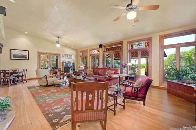 living room with lofted ceiling, ceiling fan, and light wood-type flooring