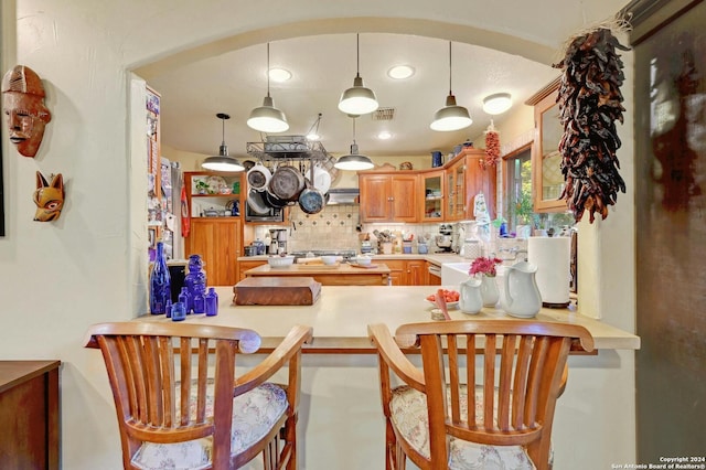 kitchen featuring pendant lighting, kitchen peninsula, decorative backsplash, and a breakfast bar