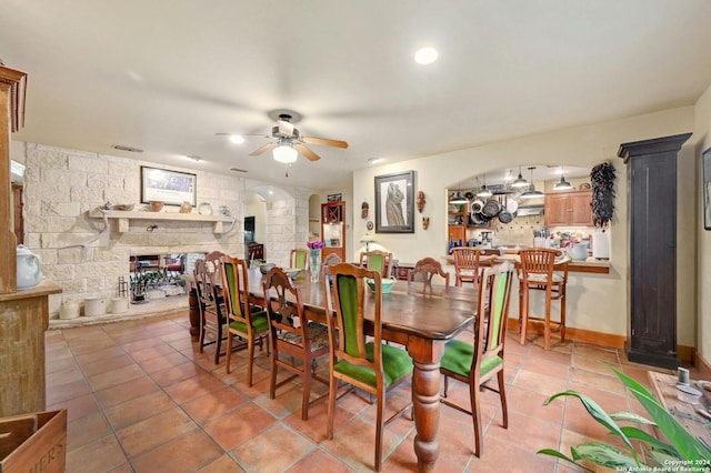 dining area with a fireplace, light tile patterned floors, and ceiling fan