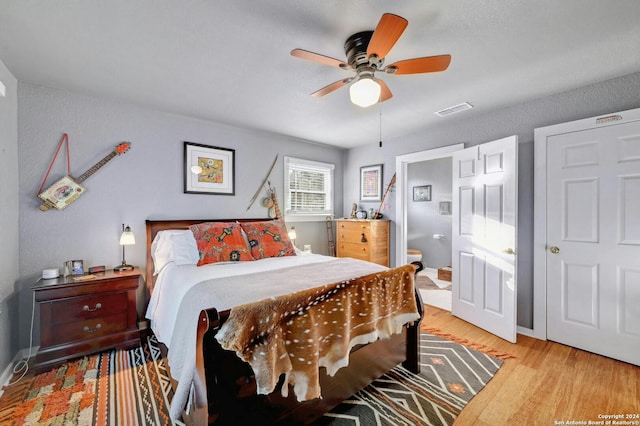 bedroom with light hardwood / wood-style floors, ensuite bathroom, and ceiling fan