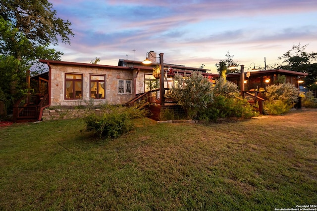 back house at dusk featuring a yard and a deck