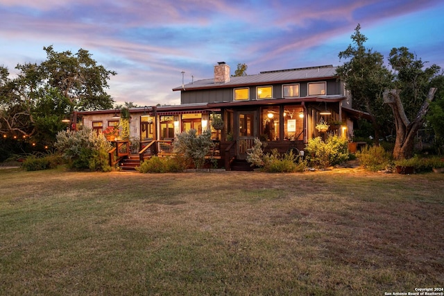 back house at dusk with a lawn