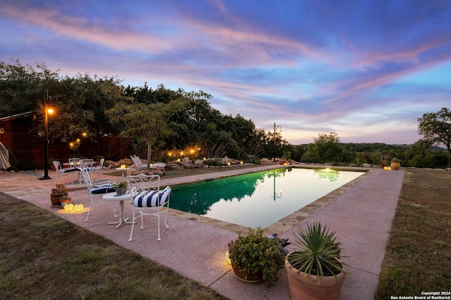 pool at dusk featuring a patio