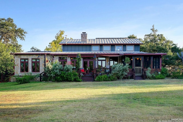 rear view of house featuring a lawn and a porch