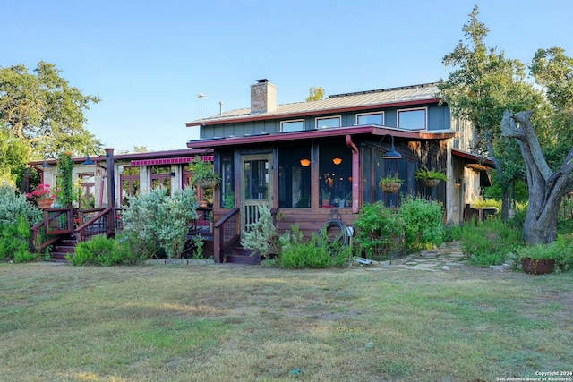 back of property with a lawn and a sunroom