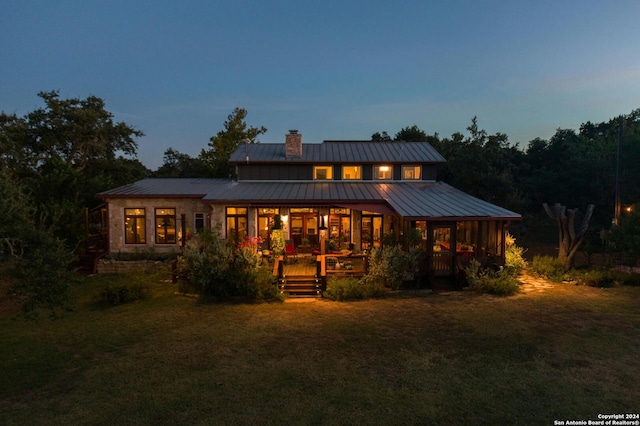 back house at dusk featuring a yard