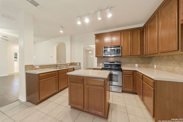 kitchen with sink, kitchen peninsula, decorative backsplash, light tile patterned floors, and appliances with stainless steel finishes