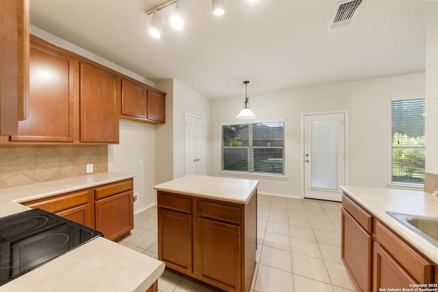 kitchen featuring stove, tasteful backsplash, pendant lighting, a center island, and light tile patterned flooring