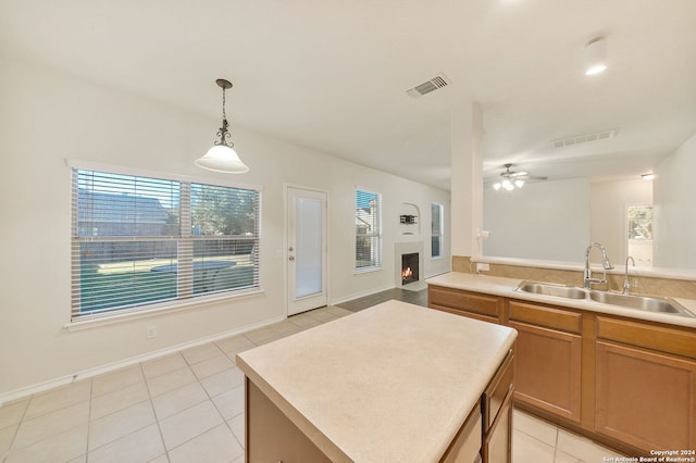 kitchen with ceiling fan, sink, light tile patterned floors, decorative light fixtures, and a center island