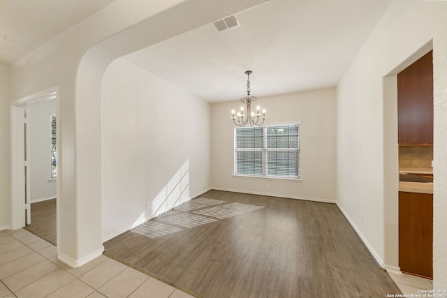 unfurnished dining area with light wood-type flooring and a chandelier