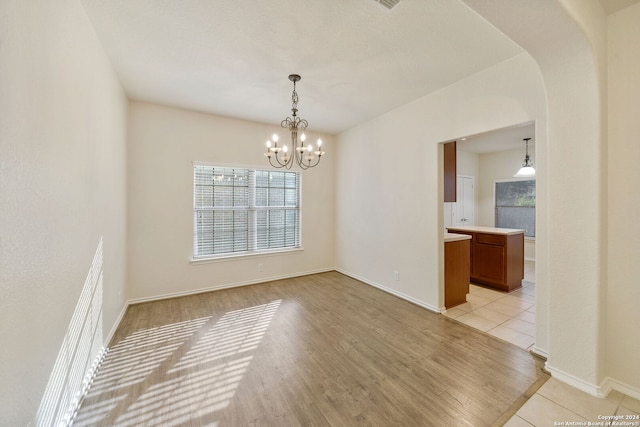 unfurnished dining area featuring light hardwood / wood-style floors and an inviting chandelier